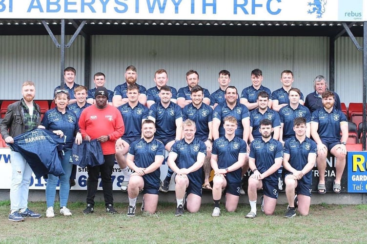 Nerys Hywel, chair of Aberystwyth Rugby Club with players from the first team accepting the clothing from the sponsors