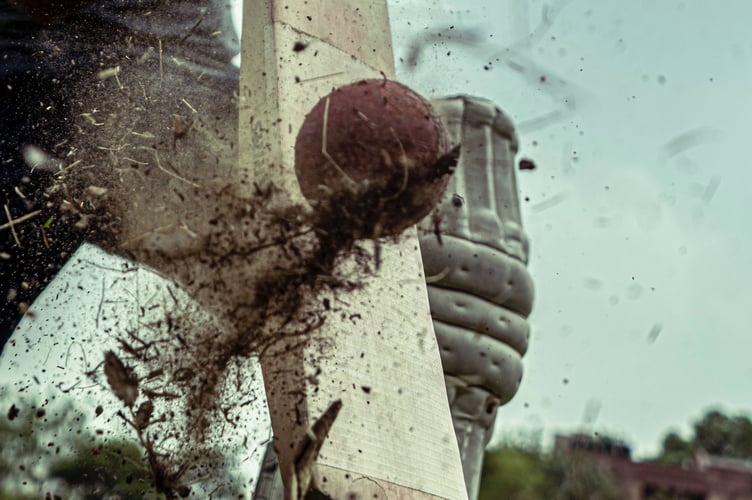 A photograph of a cricket bat hitting a ball.