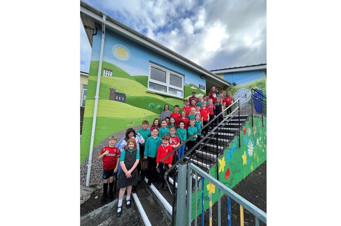 Dean Tweedy with kids from Llannon Primary School in front of the finished mural. 