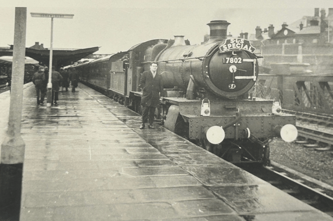 A photo taken by John (Bach) Roberts of John Hurst standing beside loco 7802 “Bradley Manor” at Shrewsbury station on Sunday 17th January 1965 on the Stephenson Loco Society excursion departing for Welshpool for the last passenger train to Oswestry and Whitchurch before closure of the line the following day