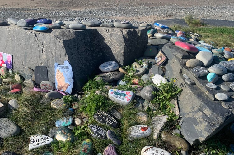 Hand painted stones scattered in a makeshift cairn along the path to Aberdyfi