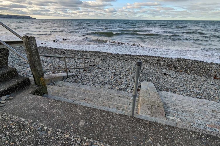 Sand and stones pile high covering handrails and restricting access to the beach