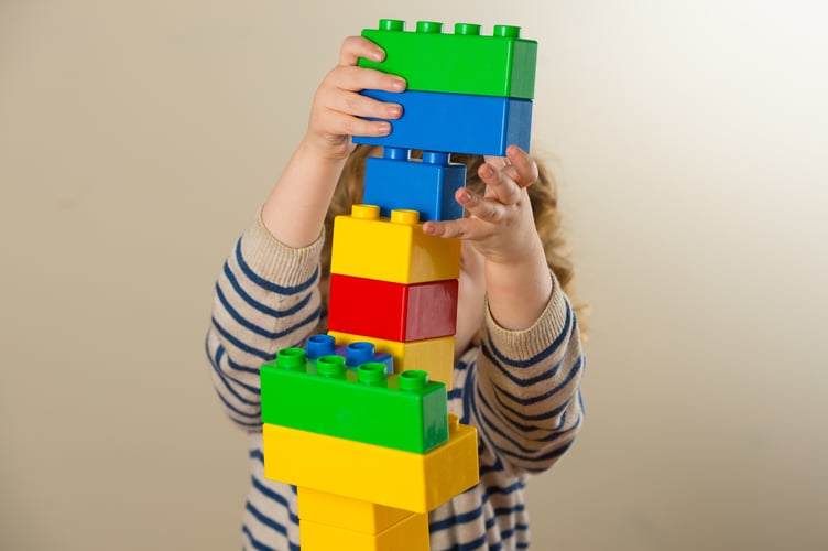 A preschool age child plays with plastic building blocks.