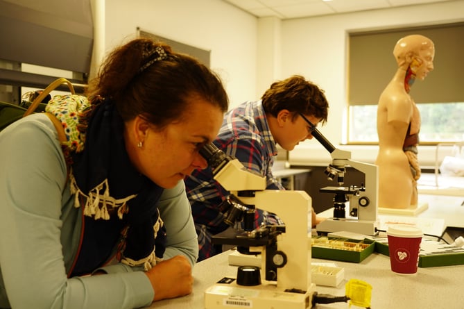 People looking through microscopes in the science labs at the Pwllheli Community Fun Day in 2022