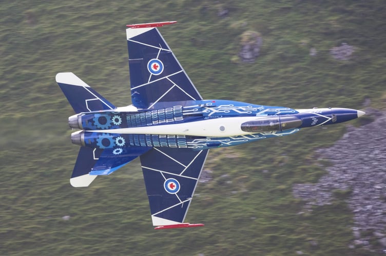 The Royal Canadian Air Force's (RCAF) CF-18 Hornet flies through the so-called Mach Loop in Wales, July 17 2024.   Jaw-dropping images show a warplane zooming through Wale's so-called Mach Loop on Wednesday (17 July). The Royal Canadian Air Force's (RCAF) CF-18 Hornet showed off its agility while it made its way to RAF Fairford as it prepares to display at the 2024 Royal International Air Tattoo. The pilot showing off his skills is Captain Caleb âTangoâ Robert, who serves as a combat-qualified element lead on the CF-18 for 425 (Alouettes) Tactical Fighter Squadron at 3 Wing in Quebec. The Mach Loop is a series of valleys in west-central Wales, notable for their use as low-level training areas for fast aircraft. The Loop is among the few places in the world where photographers can see combat aircraft flying below them.
