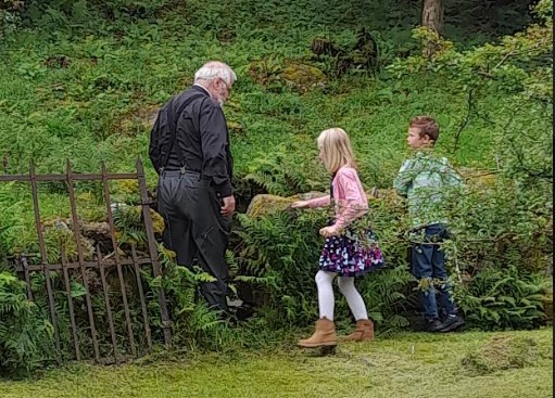 The Reverend Allan Wilcox, showing youngsters Sophia Wood, aged 6, and Ethan Wood, 8, the well at Nant Peris